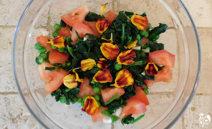 Add any herbs or flower petals into the mix. Marigolds added to peas, spinach and tomatoes in a bowl.