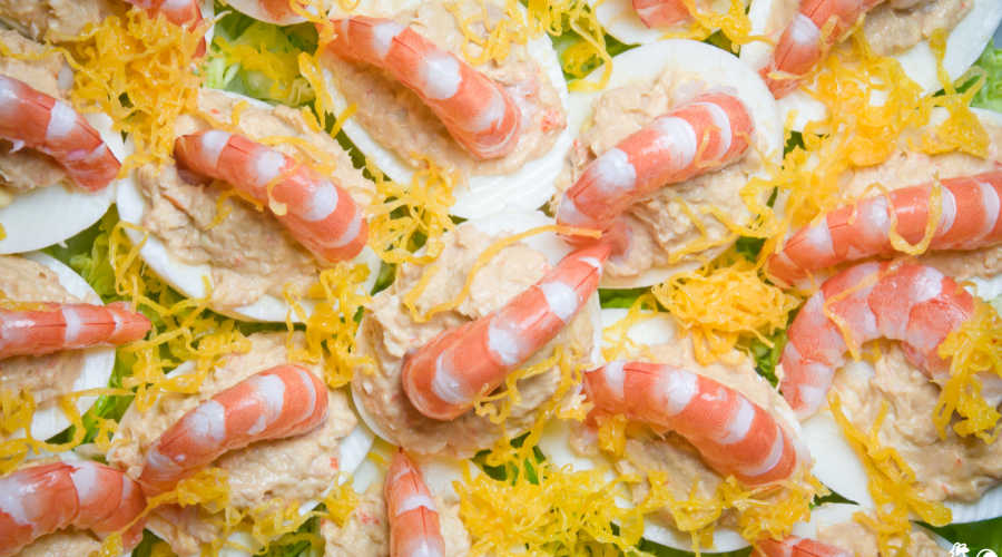 Deviled eggs with shrimp and cheese grated on top.